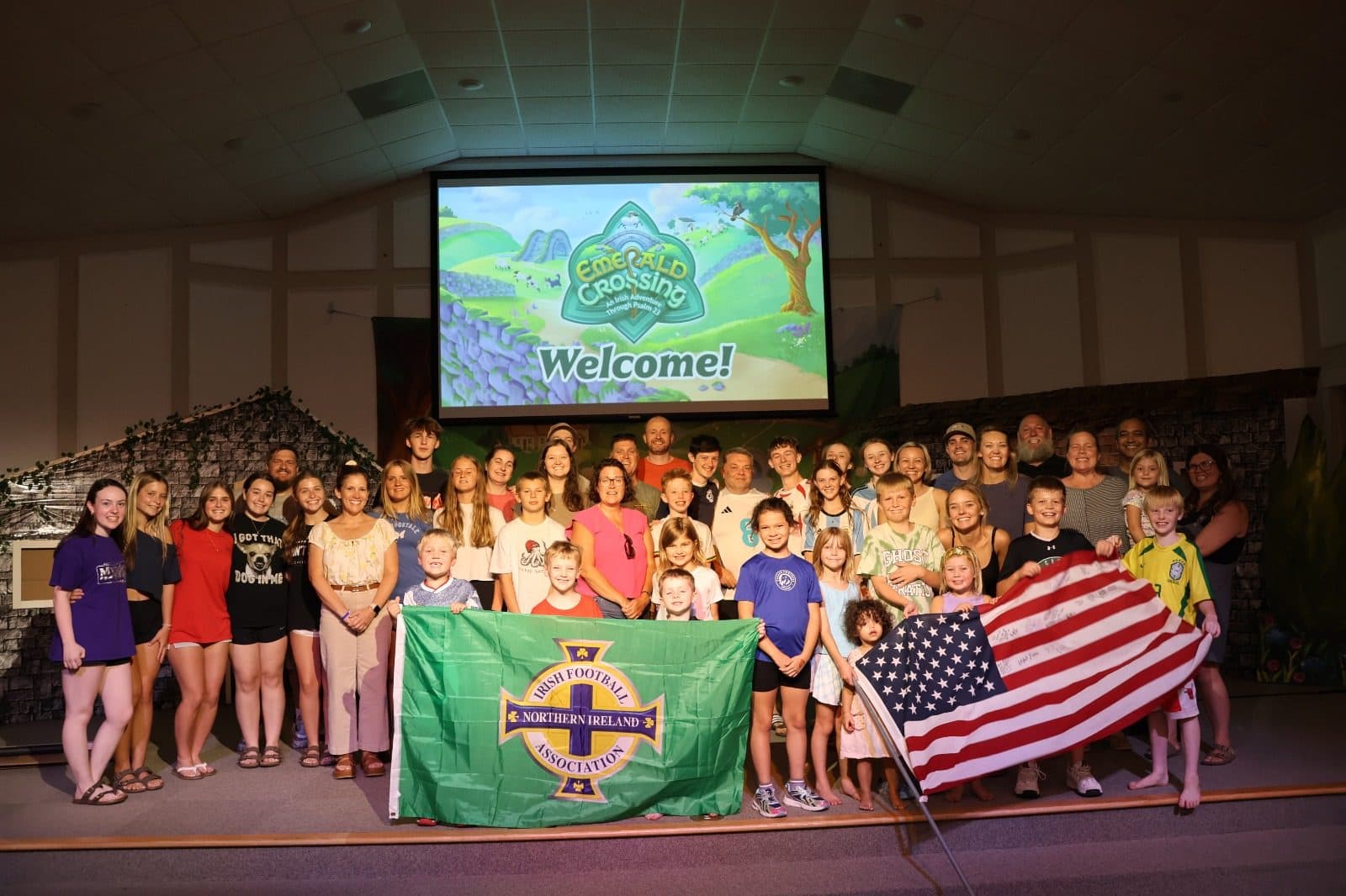 The team welcomed by a host church, holding Northern Ireland and USA flags together on stage